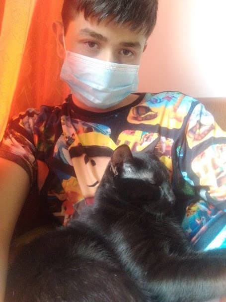 Gabriel with a white facemask and his black cat